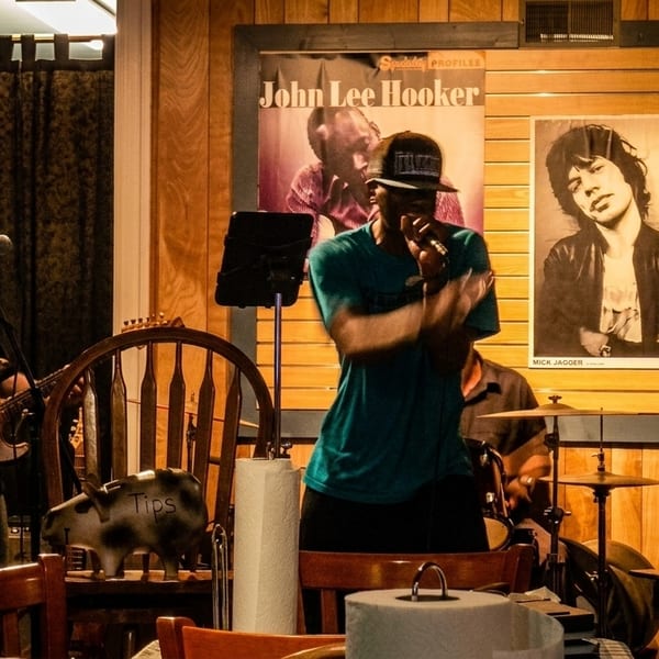 Three musicians performing live, with a guitarist, a singer, and a bassist on stage.